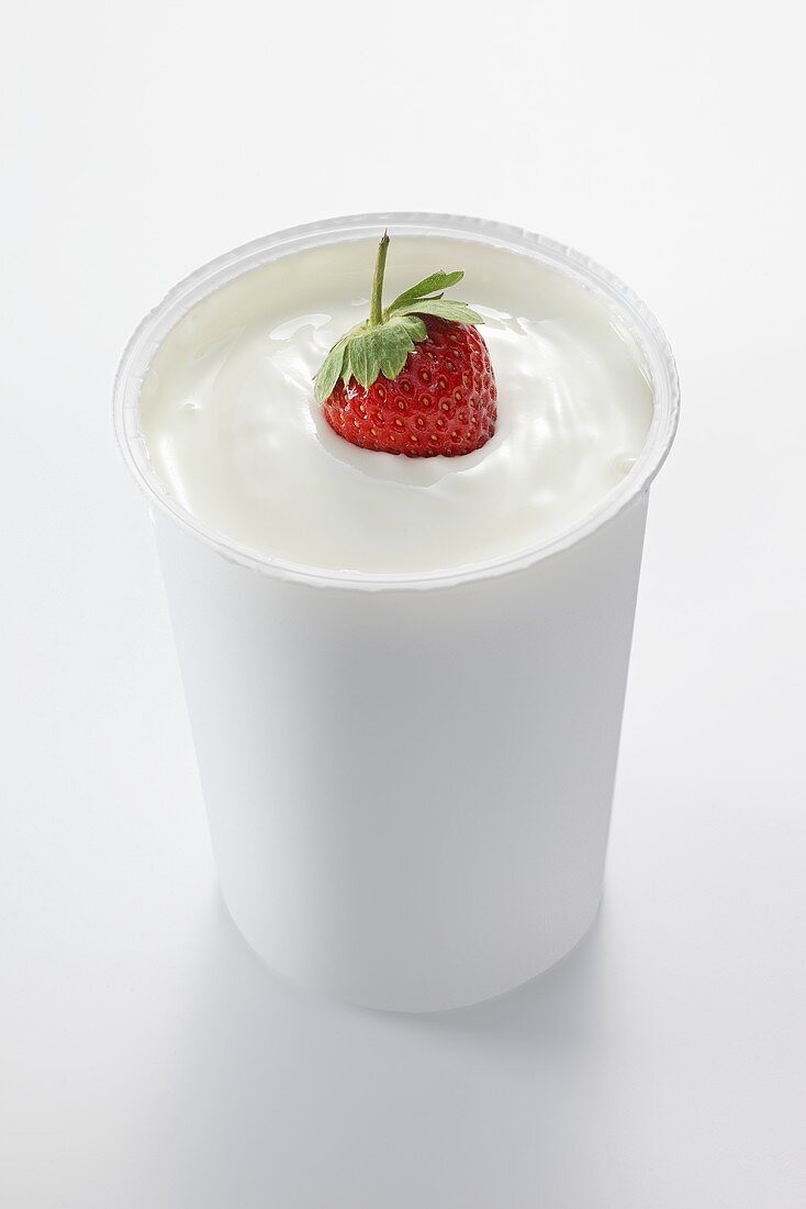A strawberry in a cup of yogurt