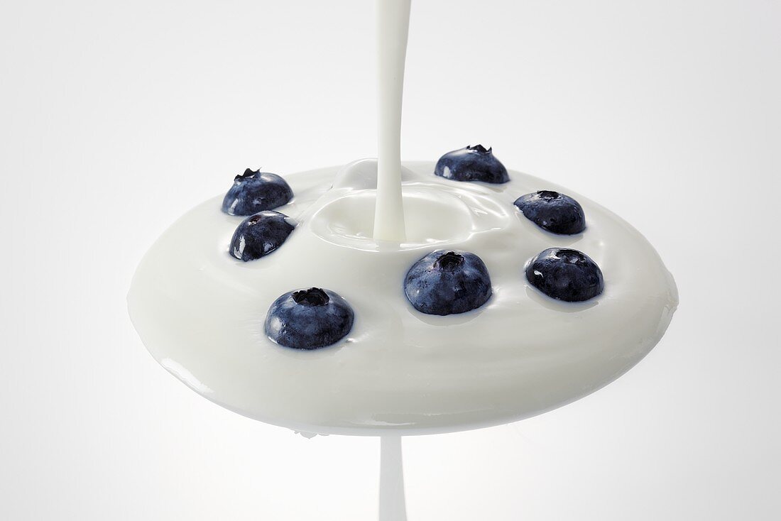 Yogurt being poured over blueberries