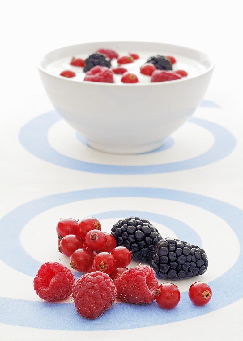 Fresh berries with a bowl of yogurt and berries in the background