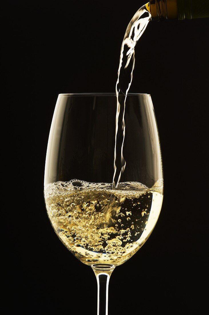 White Wine Pouring from Bottle into Glass; White Background 