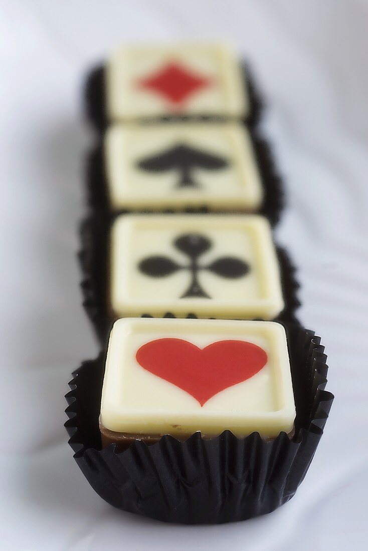 Four pralines with playing card symbols