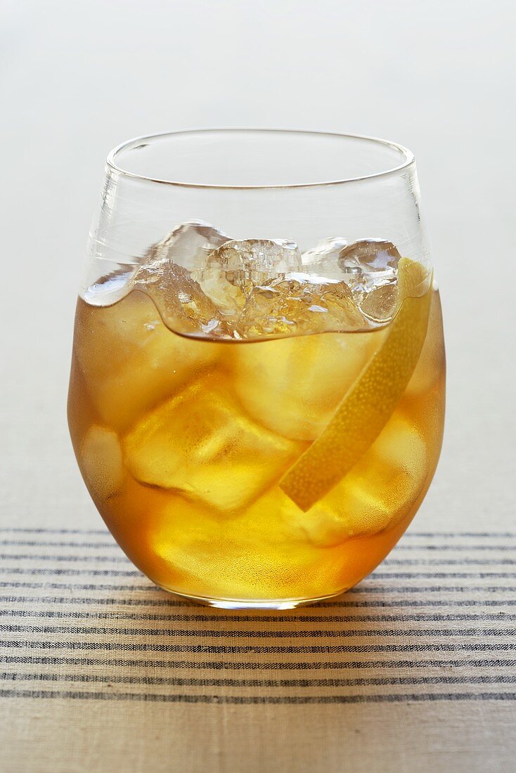 Cocktail mit Eiswürfeln und Zitronenschale