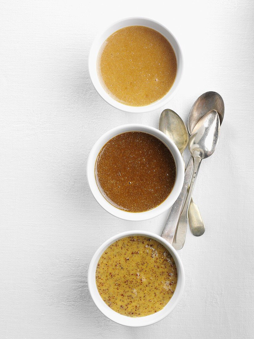 Three different types of mustard in bowls seen from above