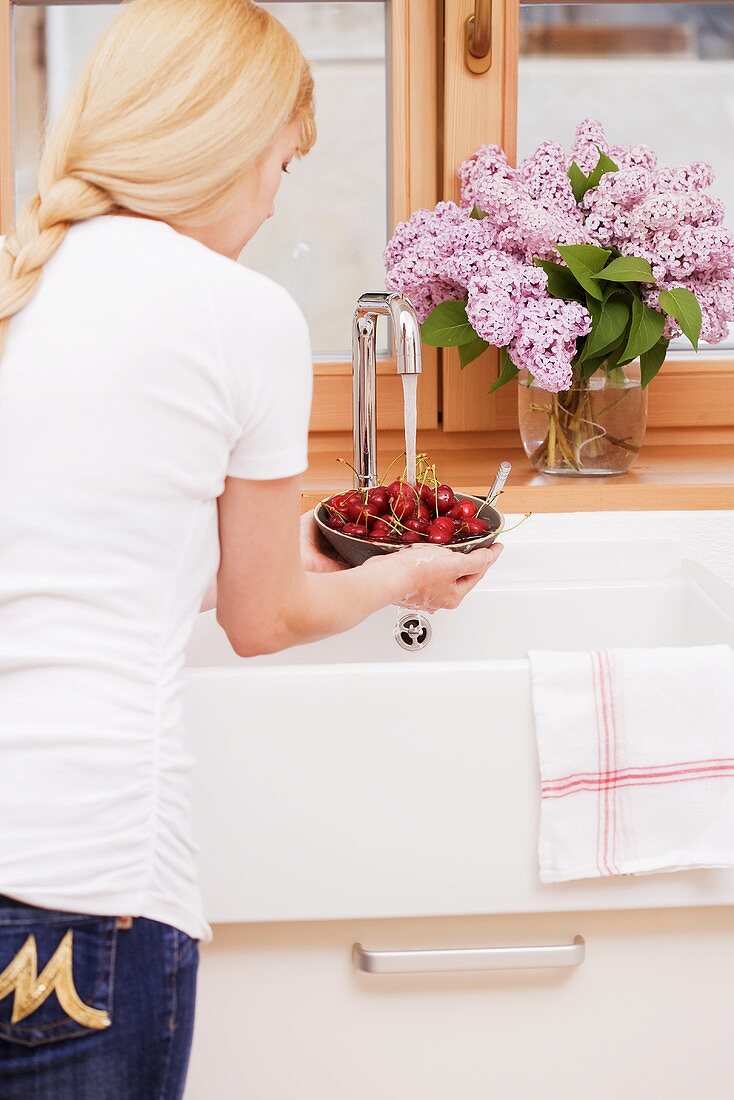 A woman washing cherries in a sink