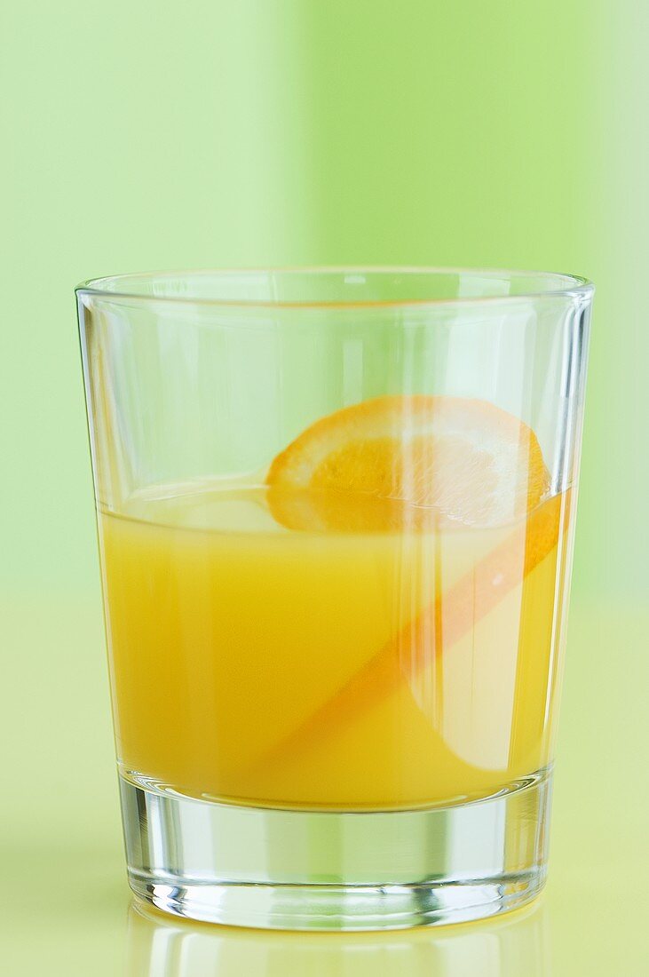 A glass of orange juice with orange slices