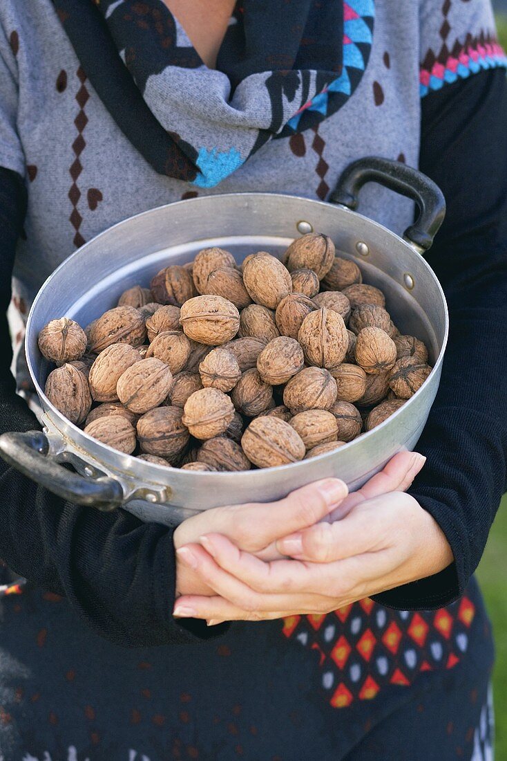 A woman holding a pot of walnuts