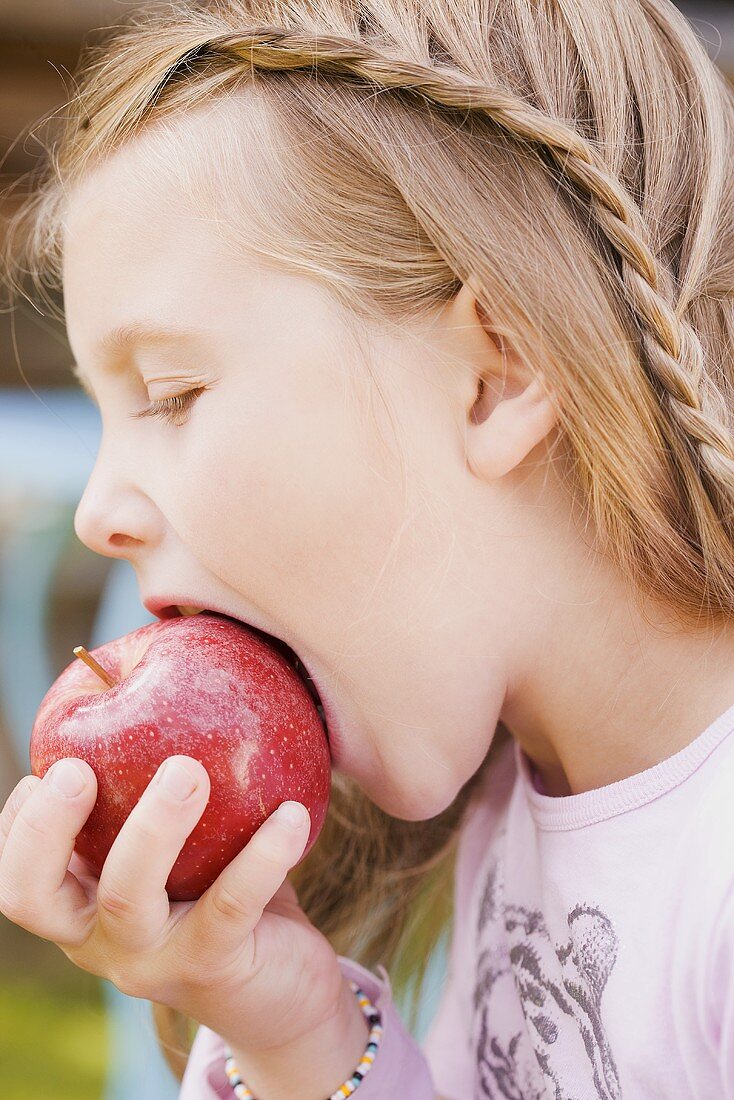 A girl biting into an apple