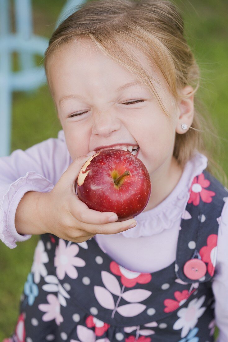A girl biting into an apple