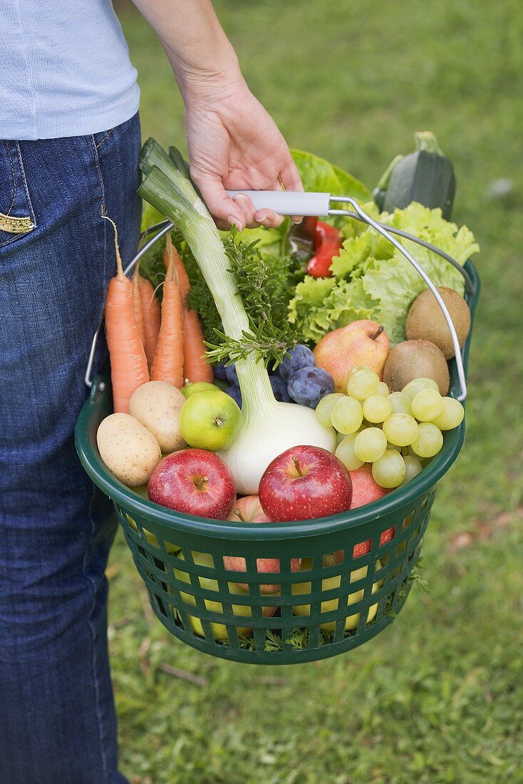 Frau trägt Korb mit Obst und Gemüse