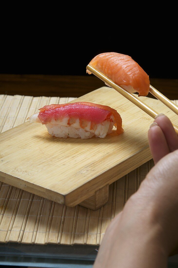 Hand holding sushi in chopsticks