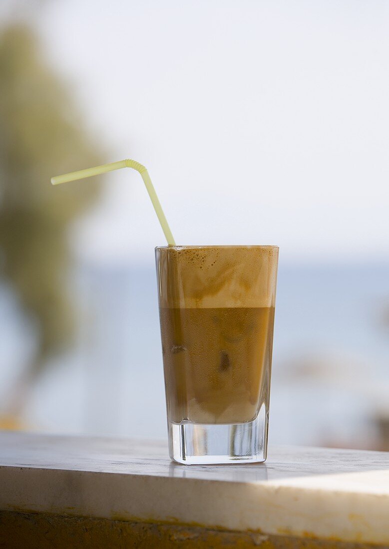 Eiskaffee mit Milch (Frappee) im Glas mit Strohhalm