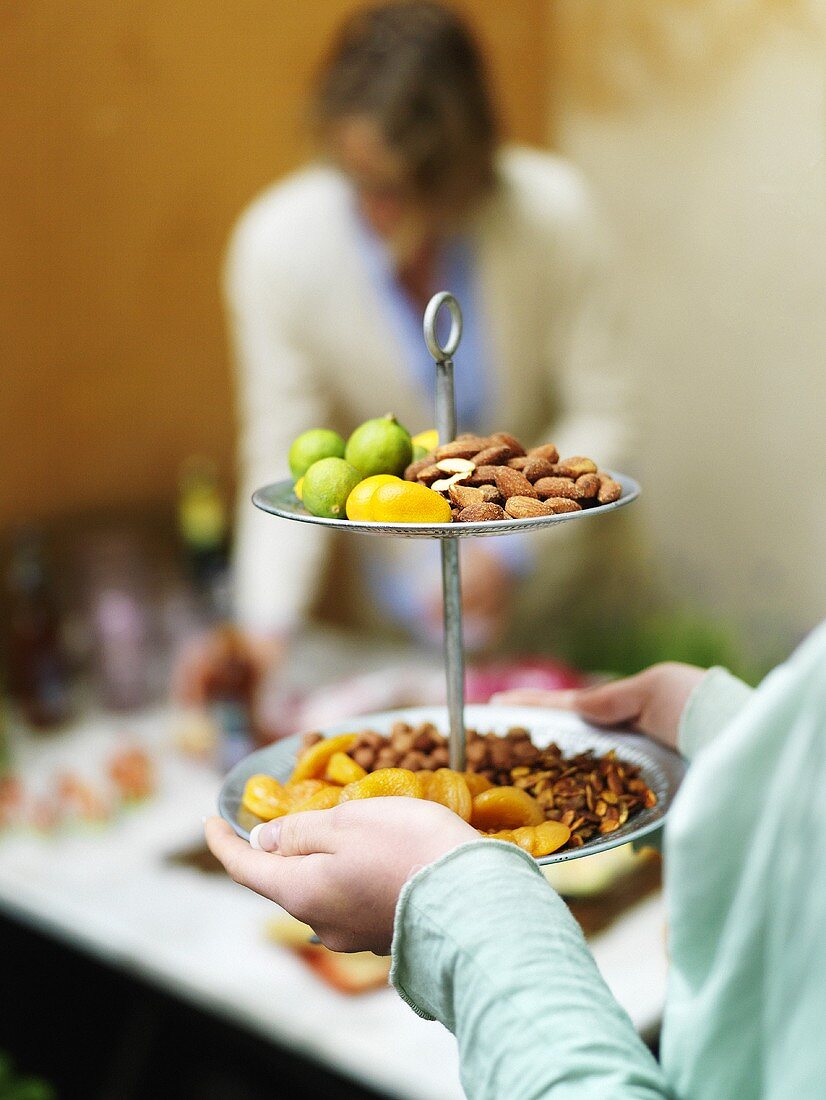 Woman serving fruit and nuts on a whatnot