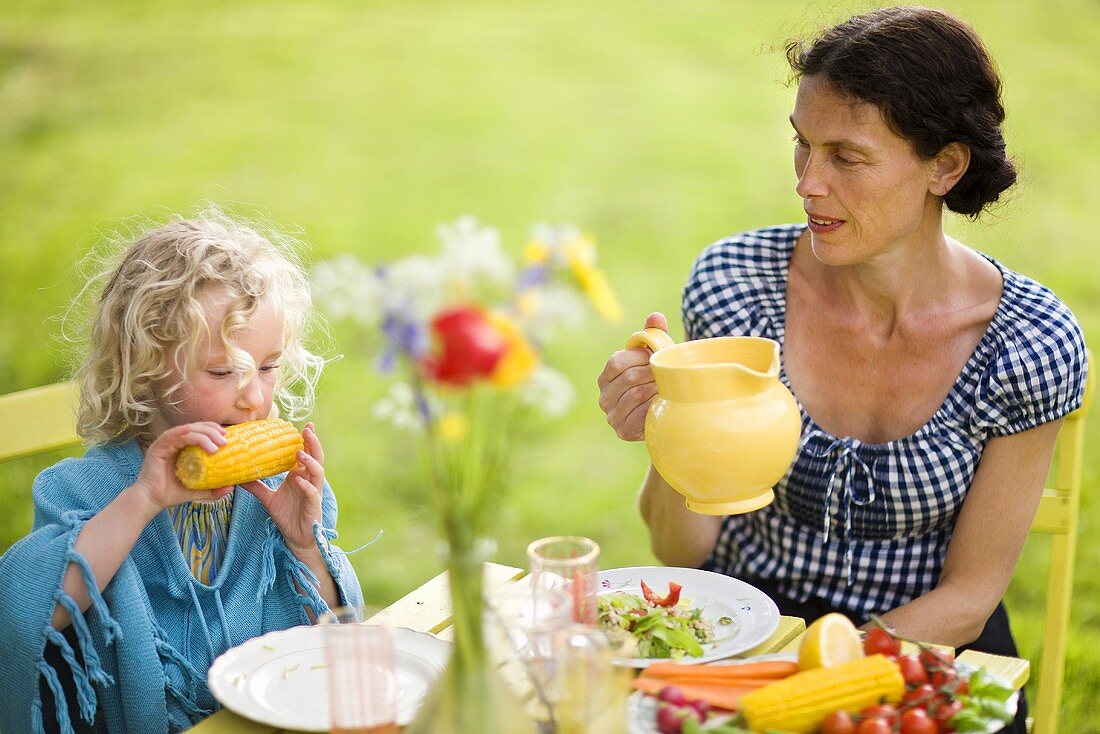 Mutter und Tochter beim Essen im Freien