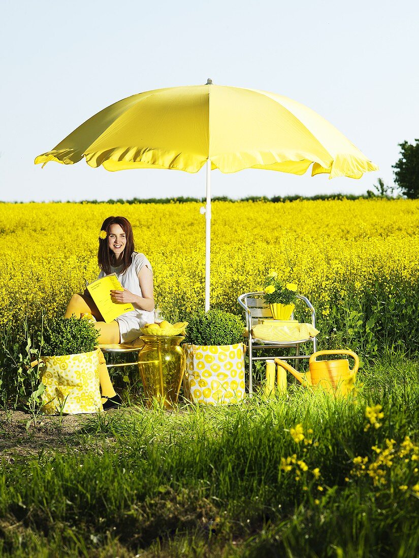 Still life in yellow; woman in front of a rapeseed field in bloom