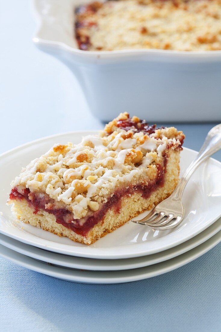 Piece of Cherry Coffee Cake on Stacked White Plates; Fork
