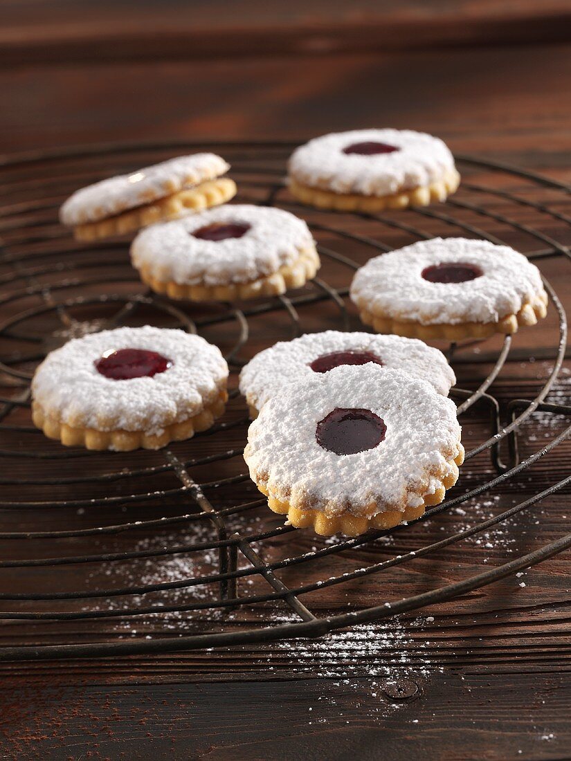 'Spitzbuben' (jelly filled cookies) with powdered sugar on a cooling rack