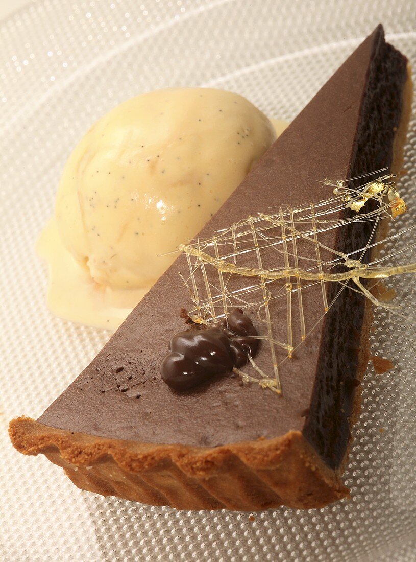 A piece of chocolate tart with vanilla ice cream with caramel decoration