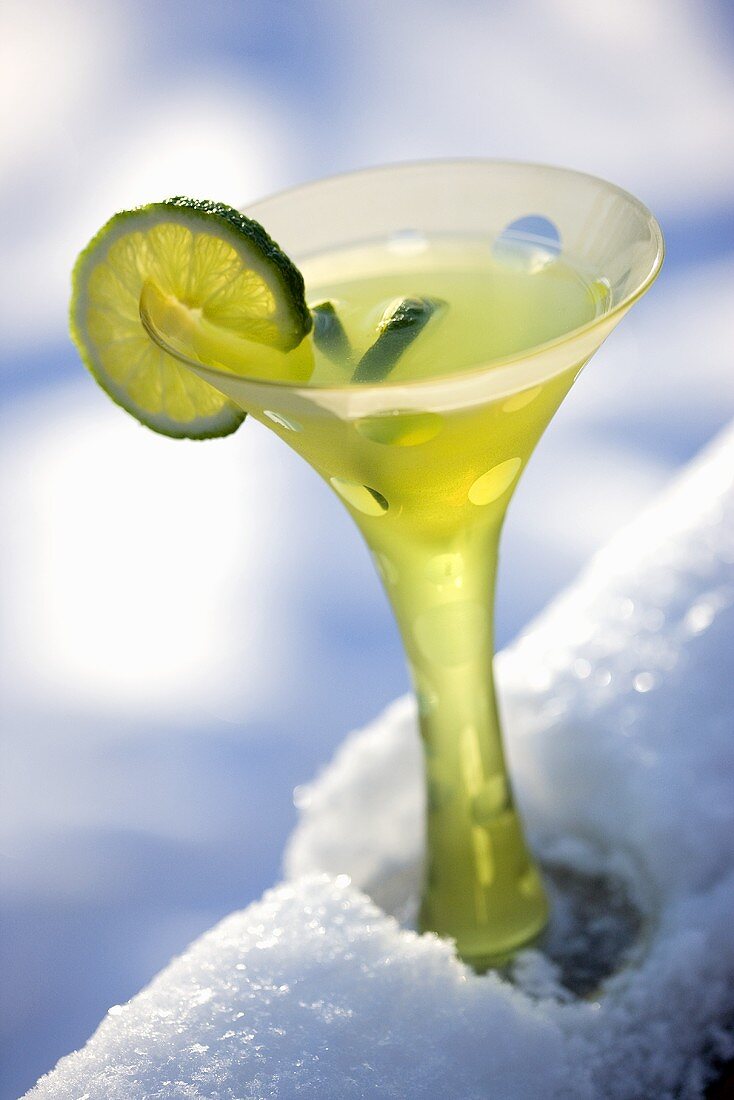 Lime Martini im Stielglas auf verschneitem Geländer