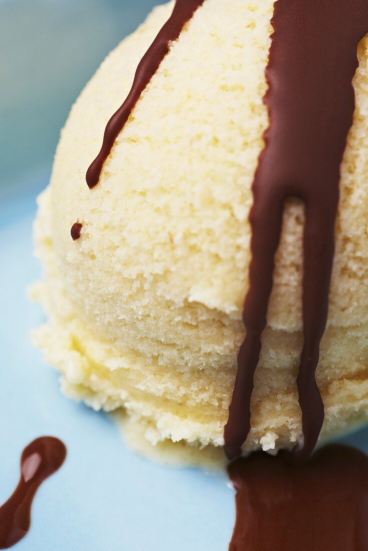 A scoop of vanilla ice cream with chocolate sauce (close-up)