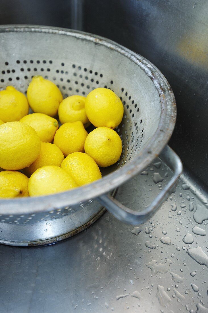 Freshly Washed Whole Lemons in a Colander in Stainless Steel Sink