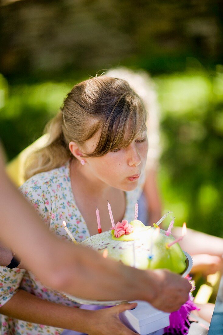 A teenager blowing out candles on a birthday cake