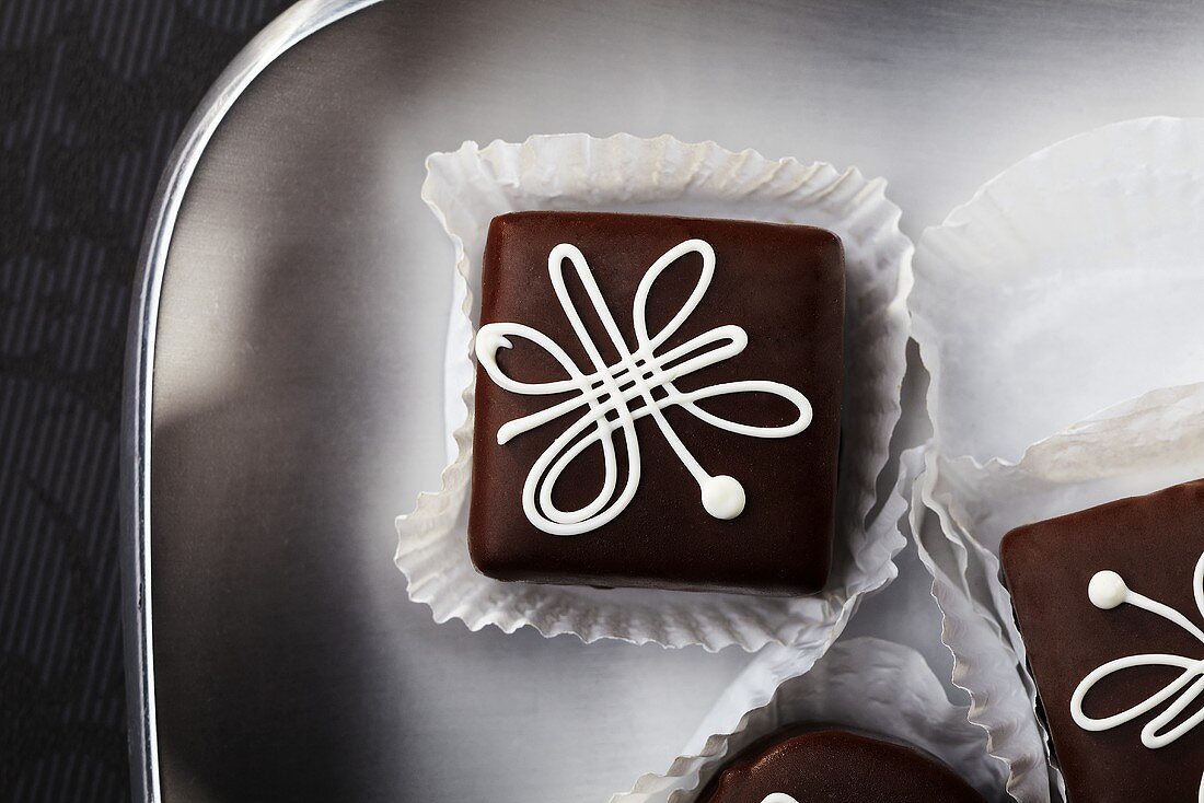 Schokoladen-Petit Fours mit weißem Zuckerguss (Draufsicht)