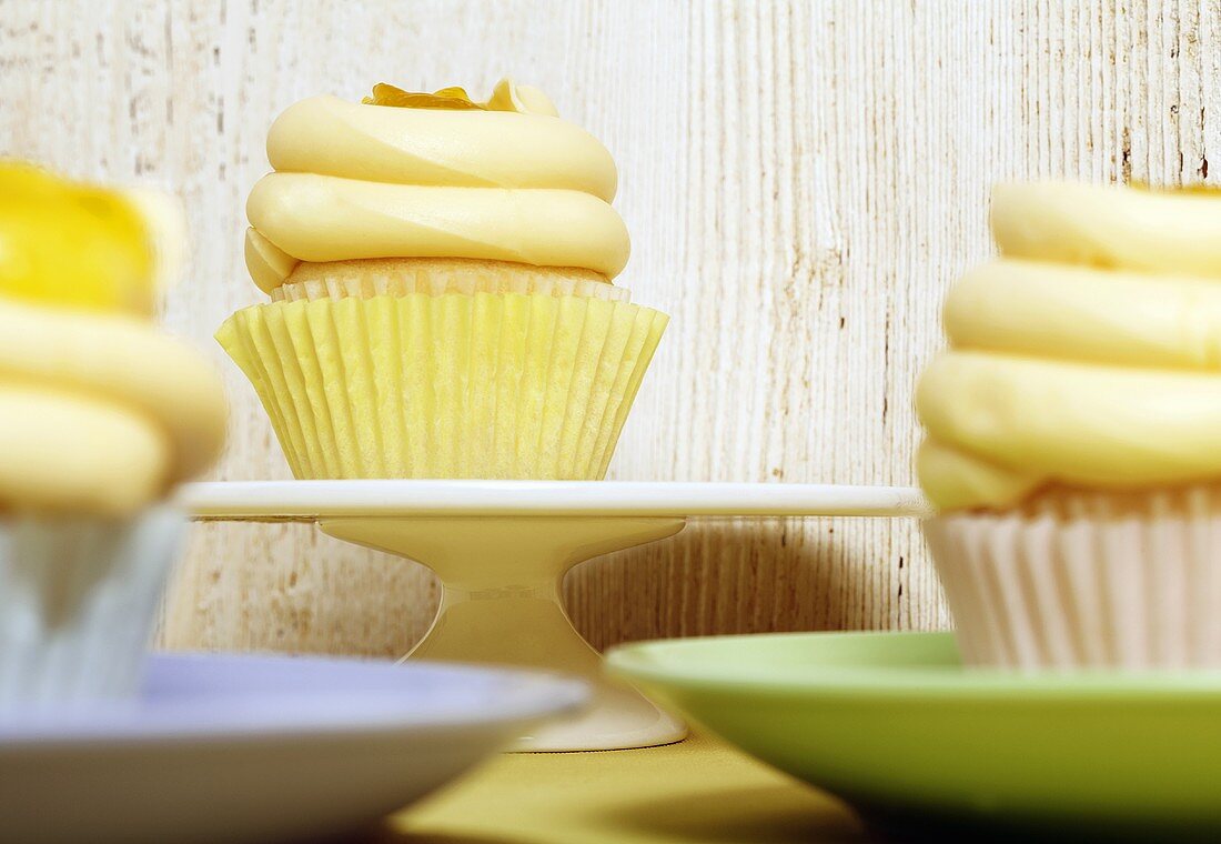 Frosted Cupcakes with Lemon Curd; On Blue, Green and White Plates