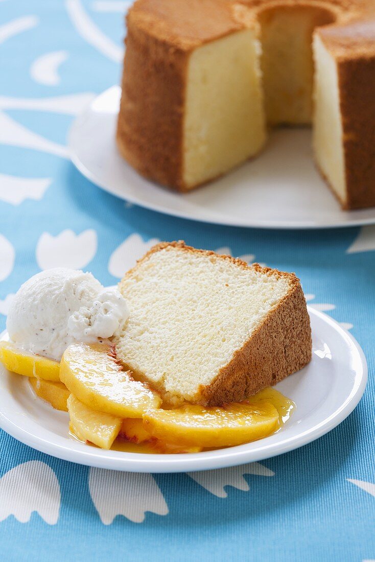 Slice of Chiffon Cake with Peaches and Ice Cream; Whole Cake in Background