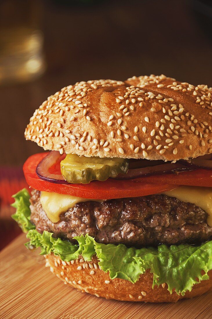 Juicy Cheeseburger with Tomato, Onion and Pickle on Sesame Seed Bun