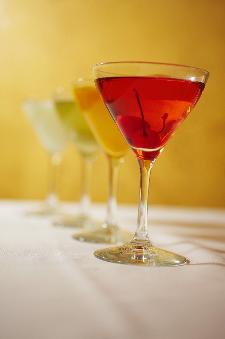 Vier verschiedenfarbige Cocktails in Martinigläsern