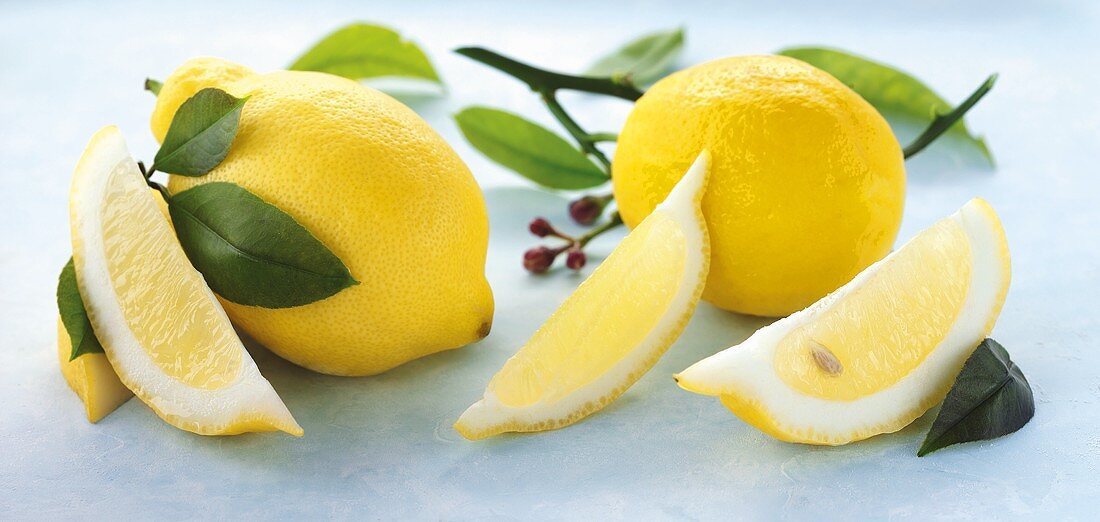 Ganze Zitronen, Zitronenschnitze und Zitronenblätter