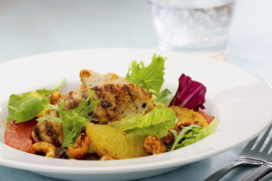 Grilled chicken fillets with citrus fruits, lettuce and cashew nuts