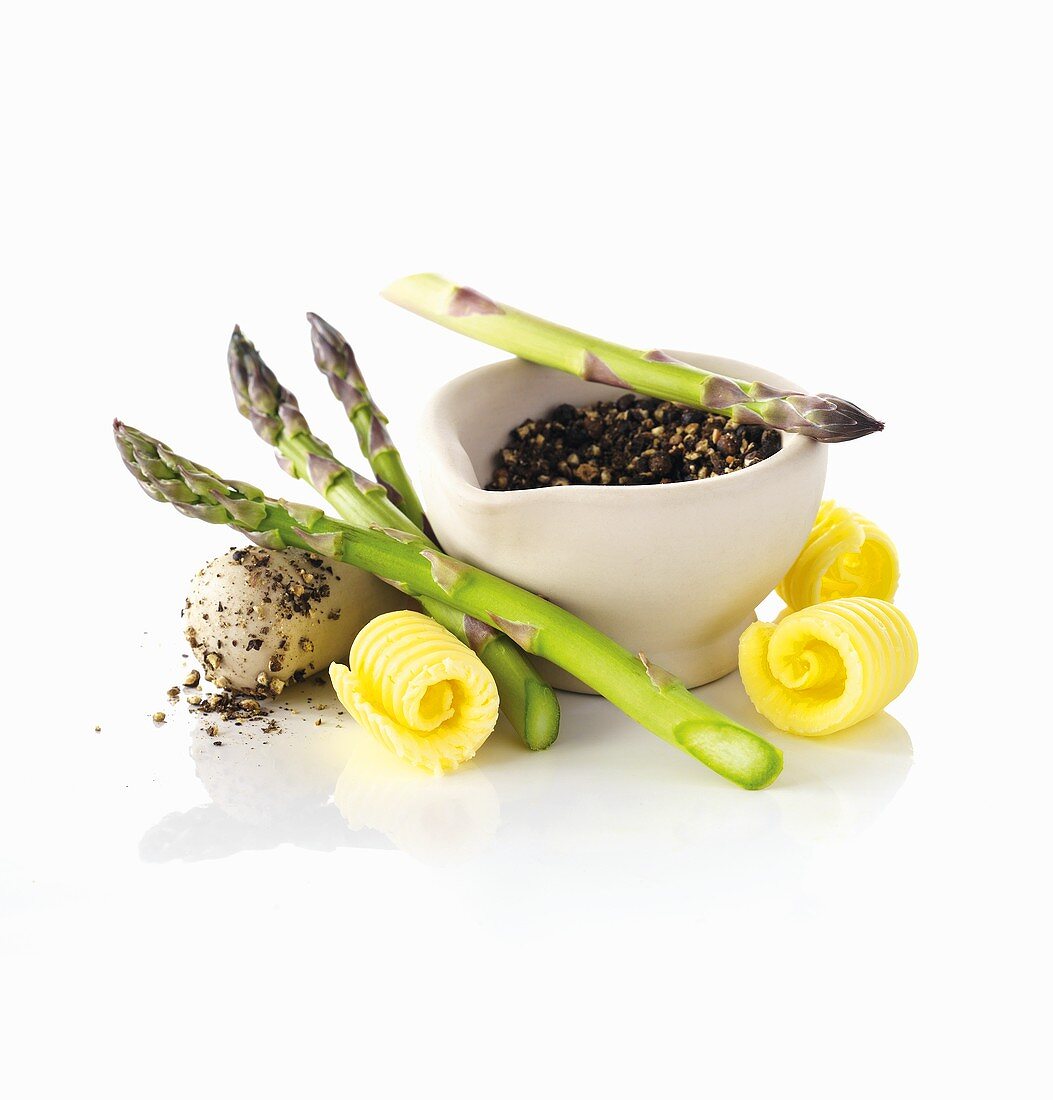 Asparagus, butter curls and peppercorns in a mortar