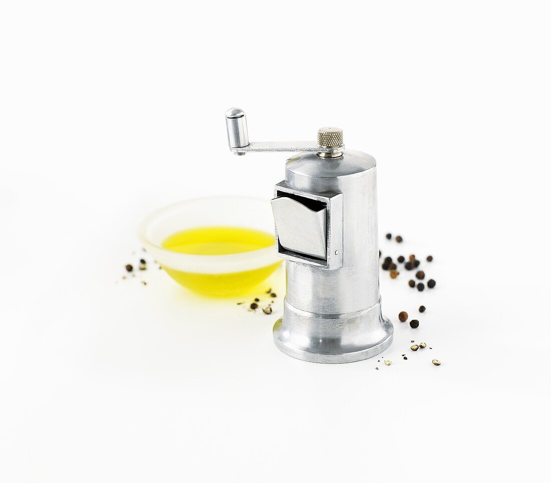 Pepper grinder, peppercorns and olive oil