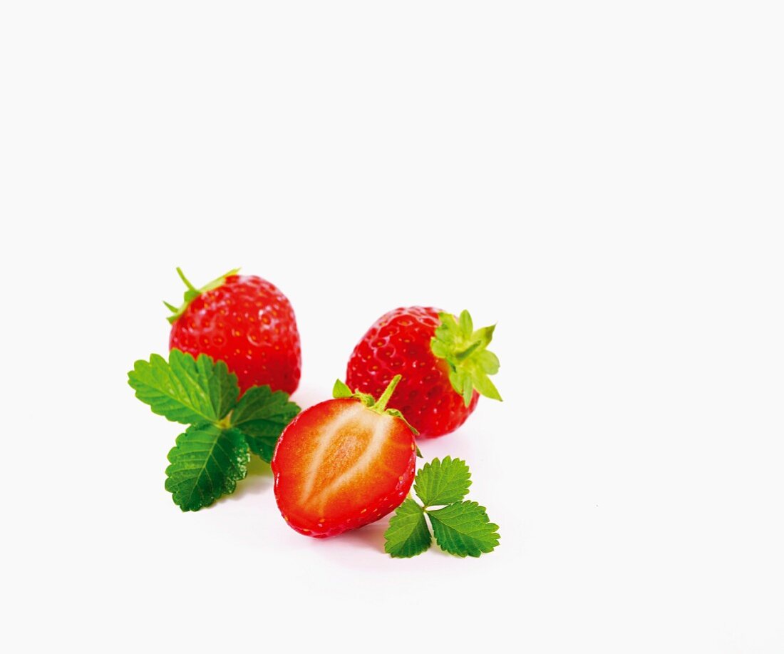 Erdbeeren mit Blättern vor weißem Hintergrund