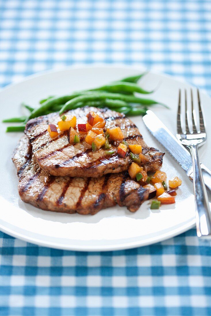 Grilled Pork Chops with Stone Fruit Salsa and Green Beans on a White Plate