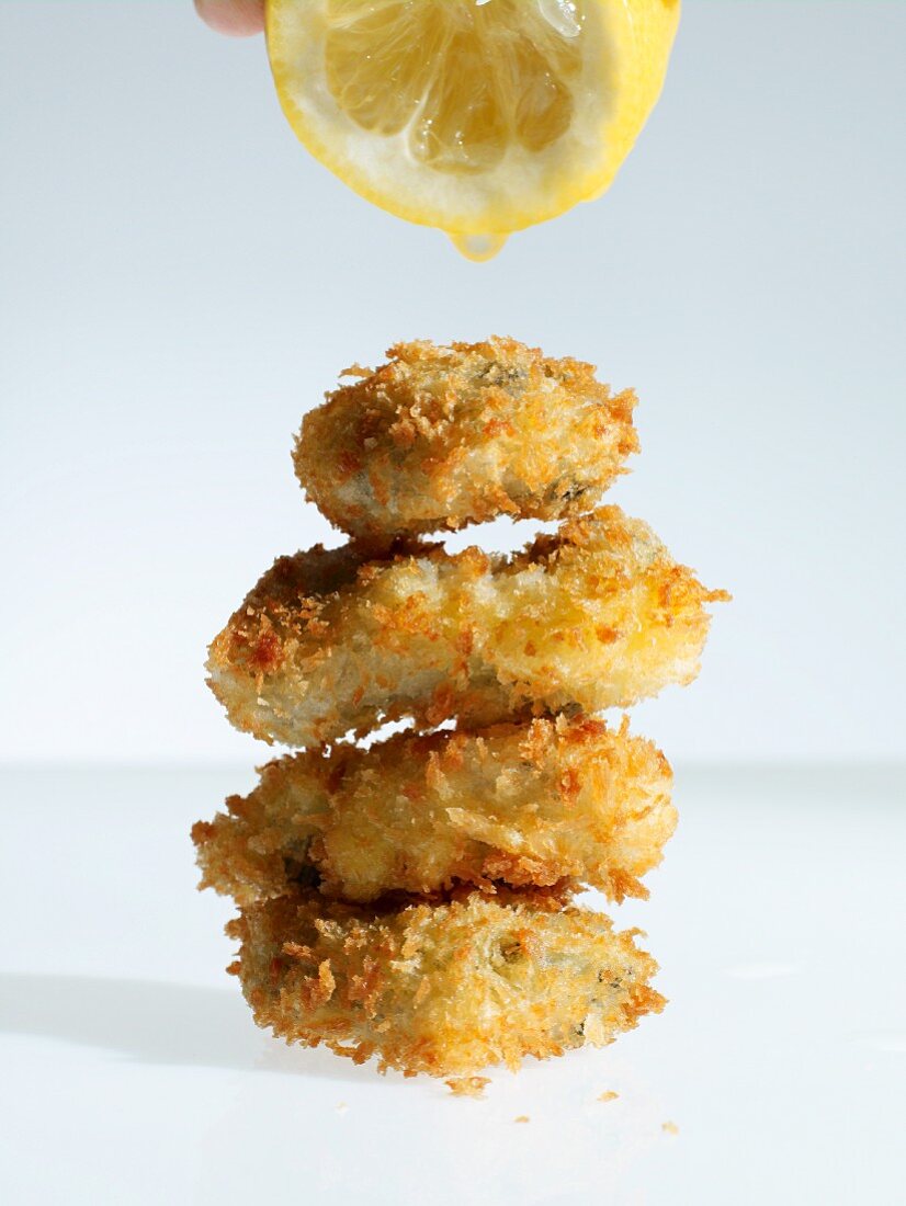 Breaded oysters being drizzled with lemon juice