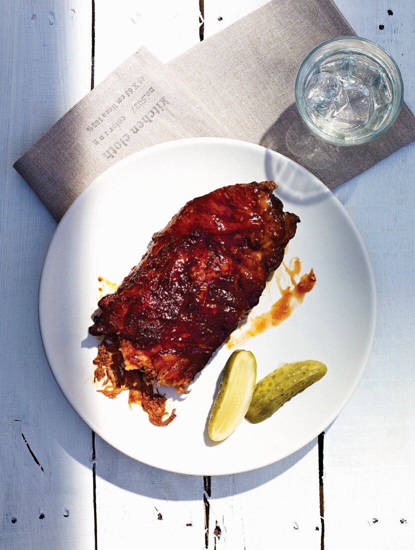Spare ribs with gherkins and a glass of water (seen from above)
