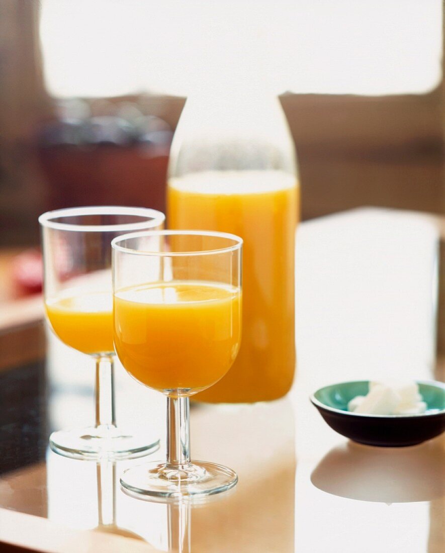 Orangensaft in Gläsern und Flasche