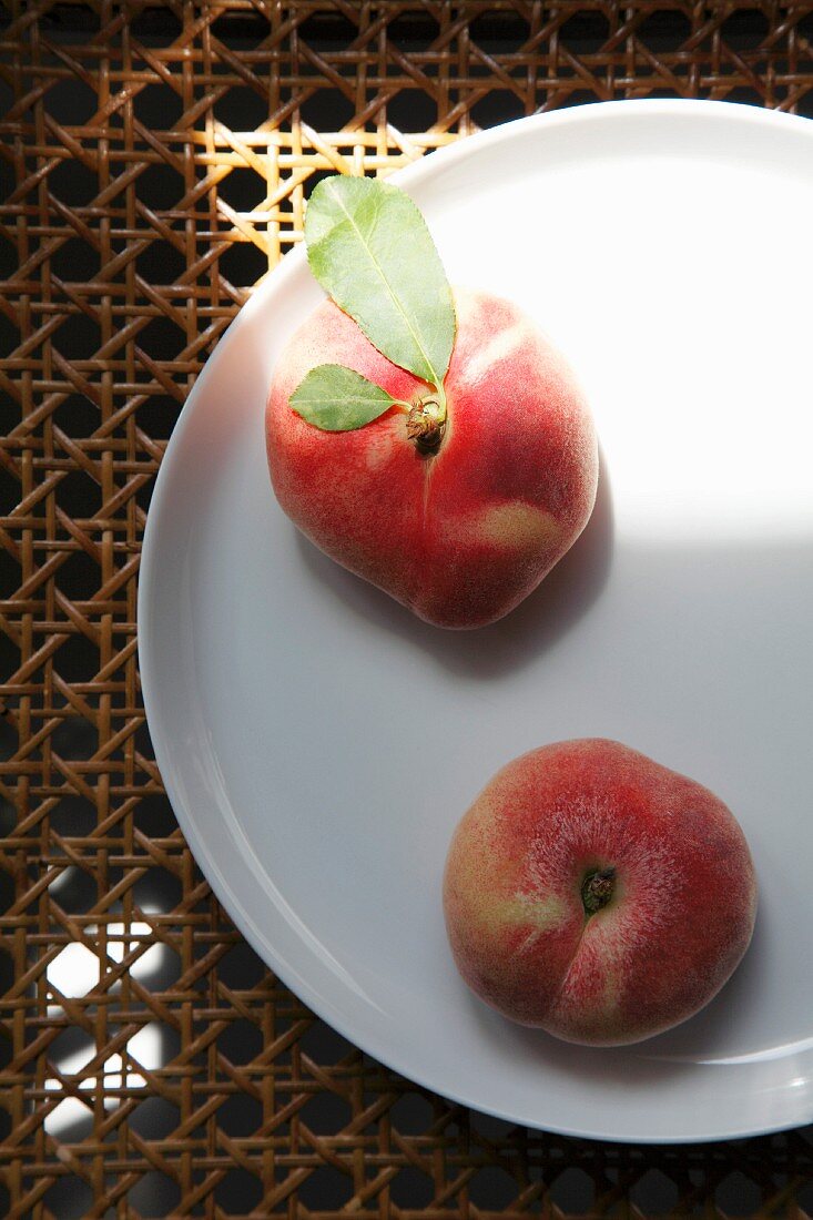 Two peaches on a plate, seen from above