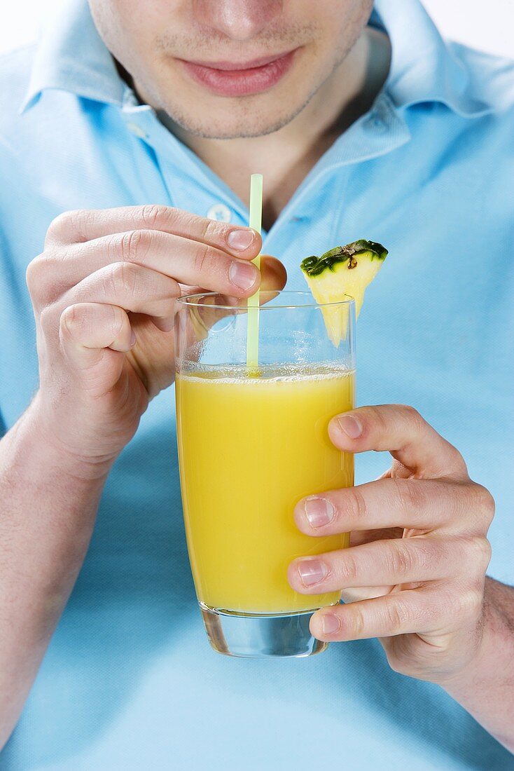 A young man drinking a glass of pineapple juice