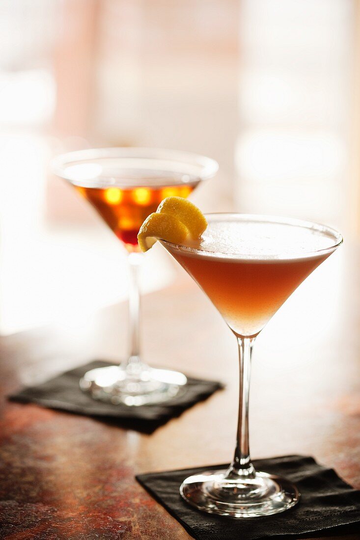 Zwei Cocktails in Stielgläsern auf Theke (Aviation Cocktail und Manhattan)