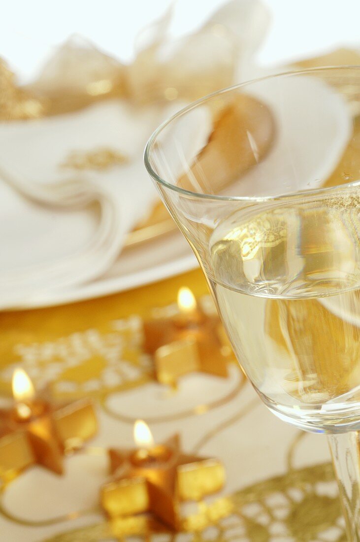 Goldener Weihnachtstisch mit Sternkerzen und Weinglas