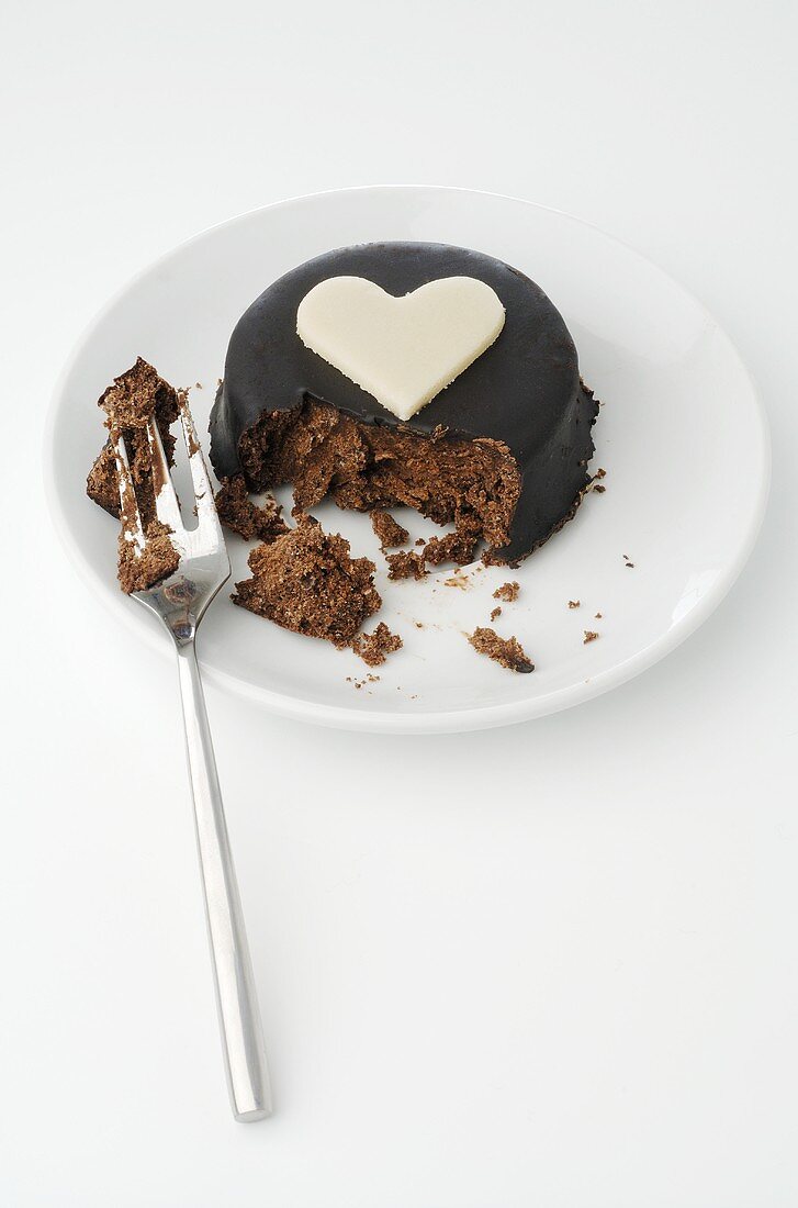 Small chocolate cake with heart, partly eaten