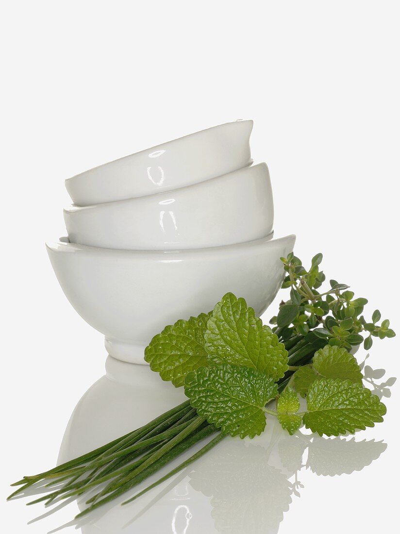 Chives, mint and thyme beside stacked bowls