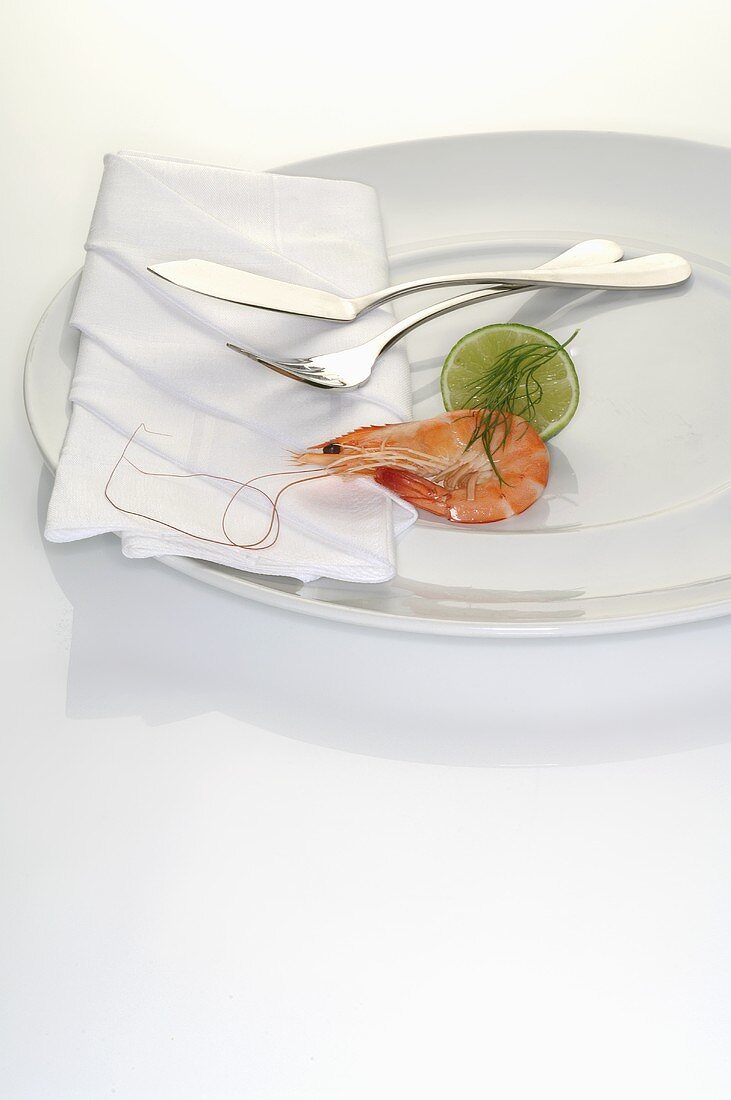 Prawn and lime on plate with napkin and cutlery