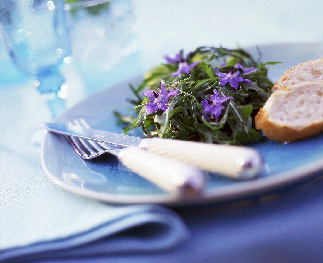 Rucolasalat mit Borretschblüten und Baguettescheiben