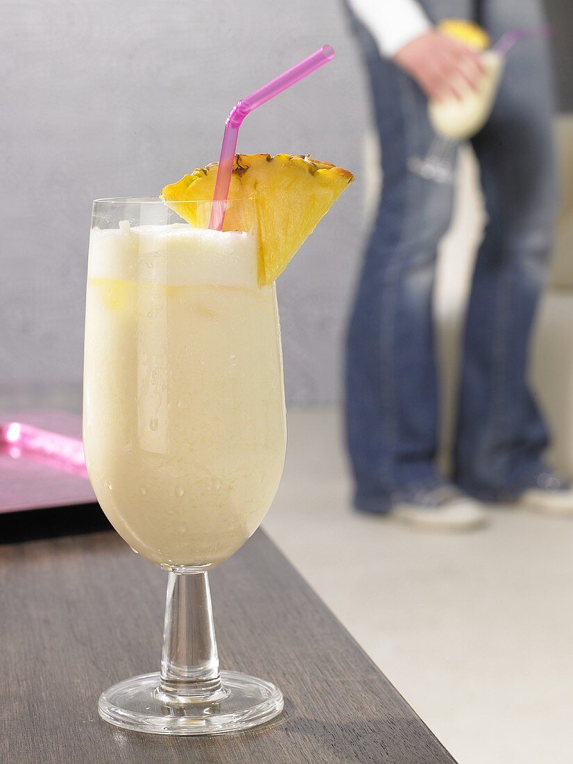 Pina Colada auf Tisch, Person im Hintergrund