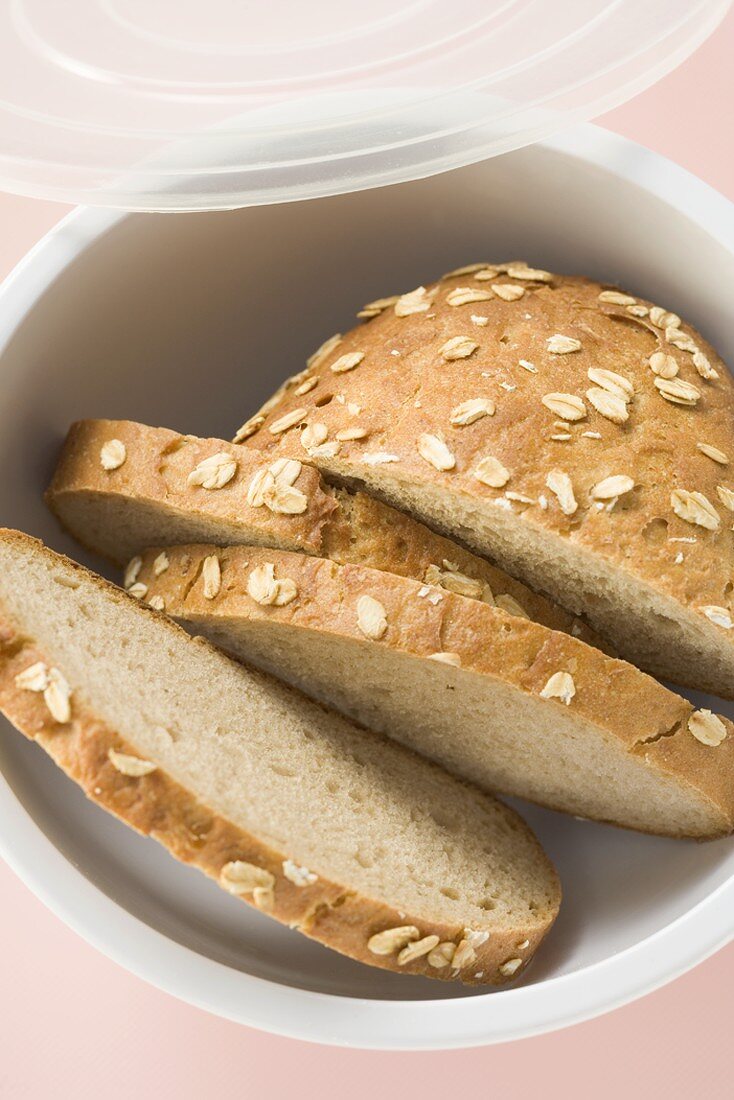 Partly sliced oat bread in plastic box