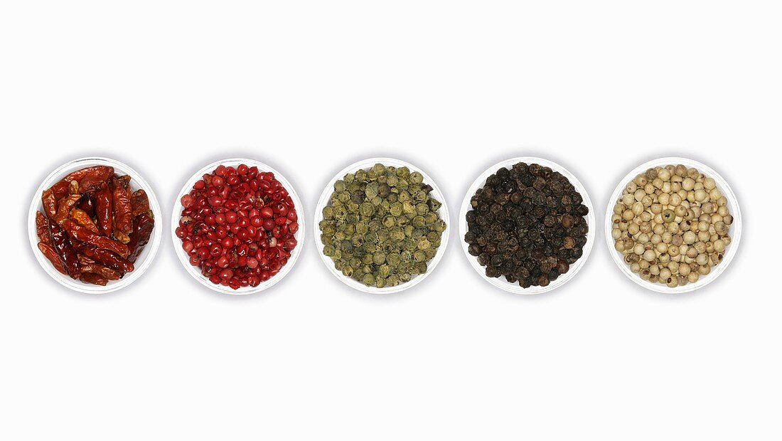 Four different types of peppercorns and dried chillies